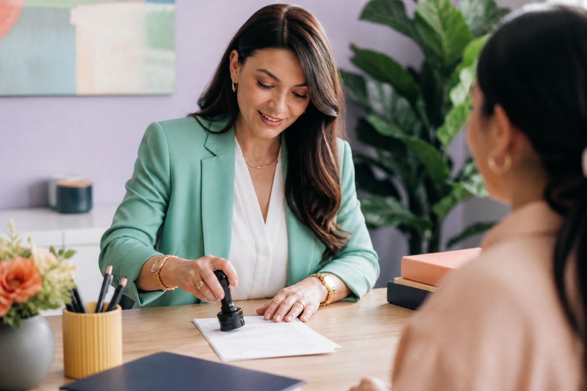 A notary public pressing a seal onto a document for a client